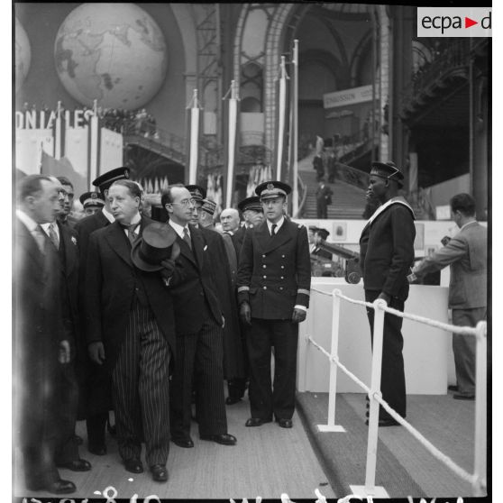 Monsieur Georges Mandel se tient devant un stand de l'exposition la France d'outremer.