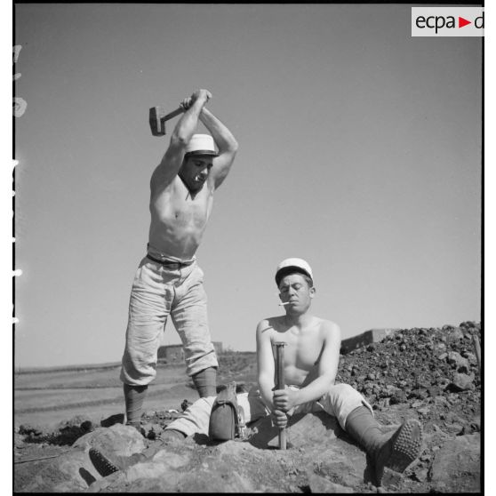 Photographie de groupe de deux légionnaires du 6e REI qui plantent un pieu métallique dans le sol.