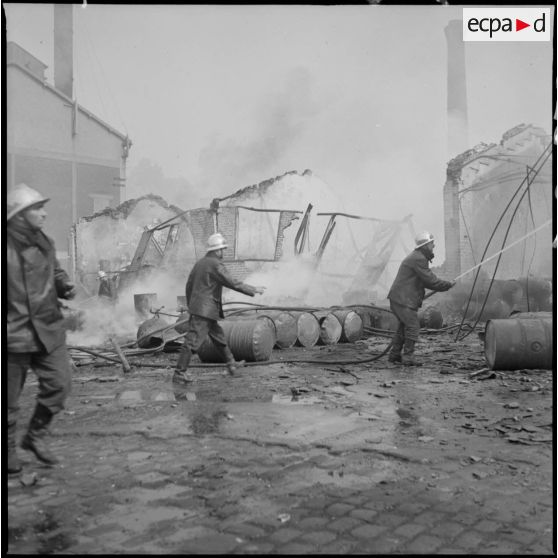 913. Des pompiers éteignent l'incendie d'un hangar détruit par le bombardement aérien allemand.