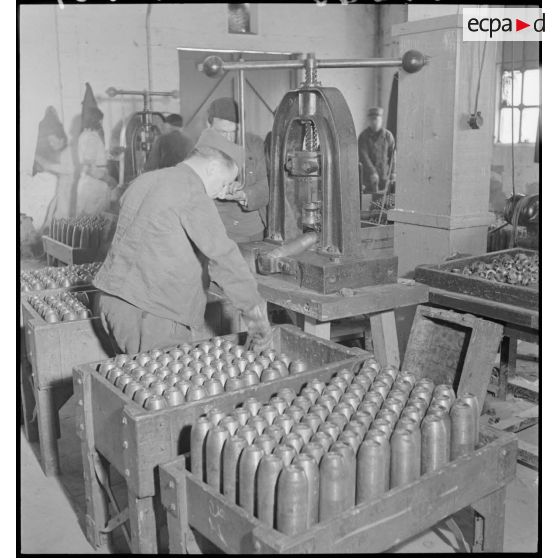 Des ouvriers sertissent des obus.