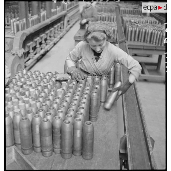 Une ouvrière range des obus.