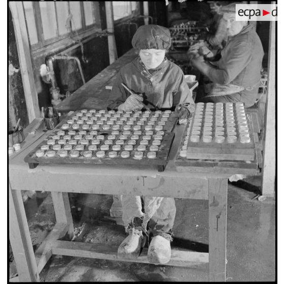 Une ouvrière travaille sur ce qui semble être des amorces d'obus.