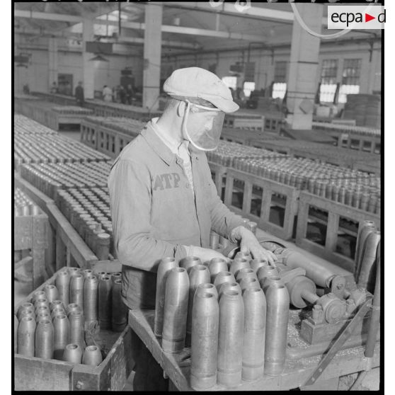 Un ouvrier tourne des corps d'obus sur une machine-outil.