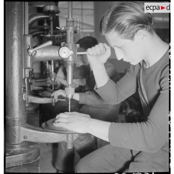 En atelier un apprenti de la cartoucherie de Vincennes travaille sur une machine-outil.