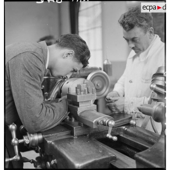 En atelier un apprenti de la cartoucherie de Vincennes travaille sur une machine-outil.