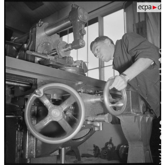 En atelier un apprenti de la cartoucherie de Vincennes travaille sur une machine-outil.