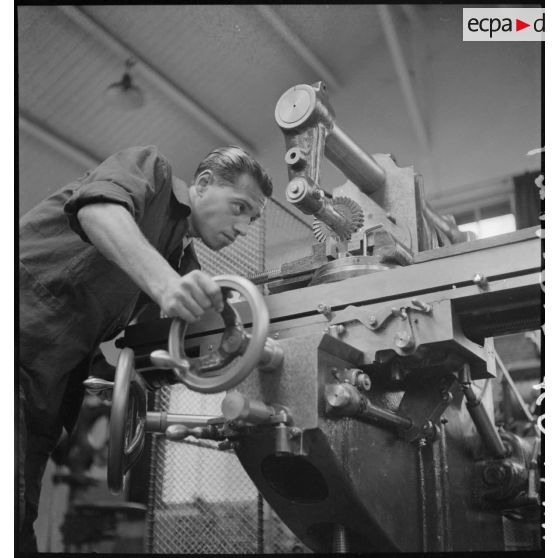 En atelier un apprenti de la cartoucherie de Vincennes travaille sur une machine-outil.