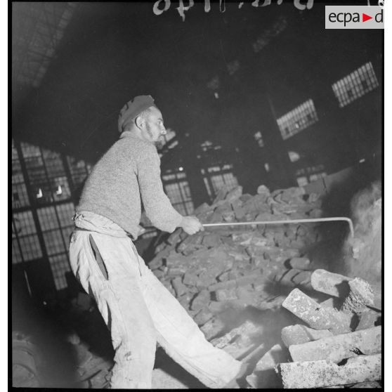 Plan moyen d'un ouvrier qui manipule du minerai de fer en vrac.