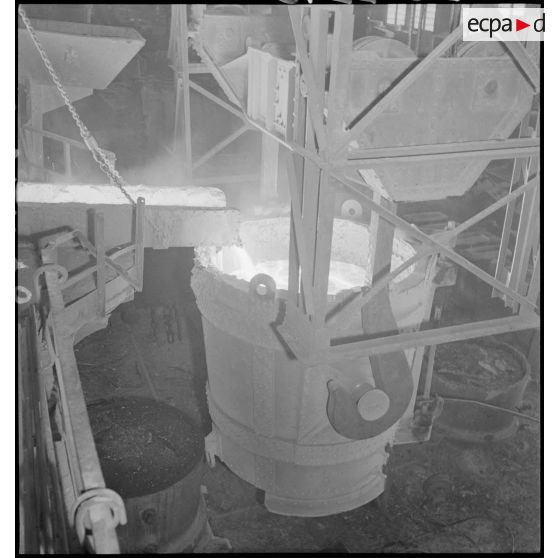 Plan général en plongée d'une coulée de métal en fusion dans un fourneau.