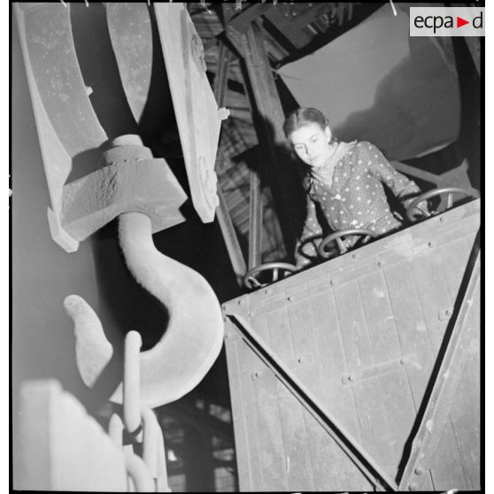 Une ouvrière est photographiée aux commandes d'une grue.