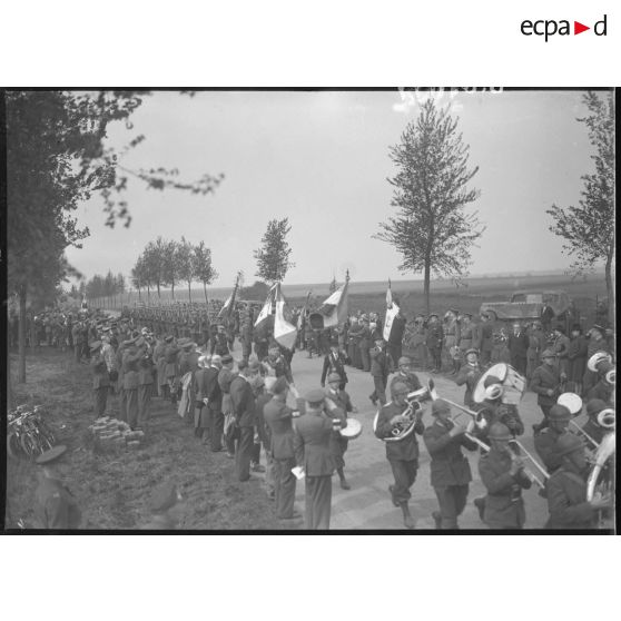 Plan général du défilé des troupes polonaises sur une route, sur les bas-côtés des officiels saluent.