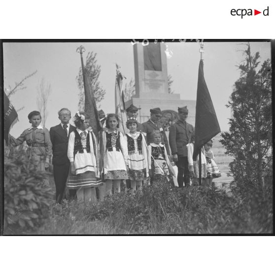 Plan général du monument commémoratif de l'offensive de la côte 140 encadré par des enfants en costume traditionnel polonais.