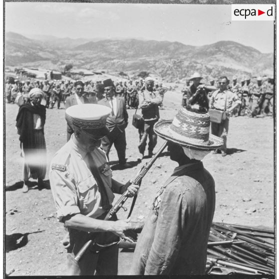 Daouia. Monsieur Verger préfet d'Orléansville remet un fusil à un homme du groupe d'autodéfense.
