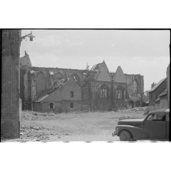 Un véhicule de la 4e compagnie de propagande de l'armée de l'air allemande devant les ruines d'une église.