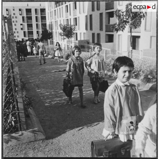 Cité Fougeroux. Rentrée des classes. Par petits groupes les enfants arrivent à l'école.