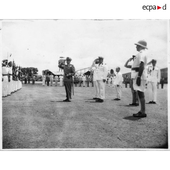 A son arrivée à l'aéroport de Bien Hoa, l'amiral Thierry d'Argenlieu passe en revue et salue les troupes en présence. [description provisoire]