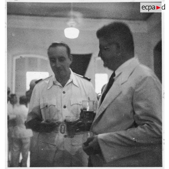 Lors de la réception du général Valluy au palais du président  Thinh, Jean Cédile prend un verre avec un officier. [description provisoire]