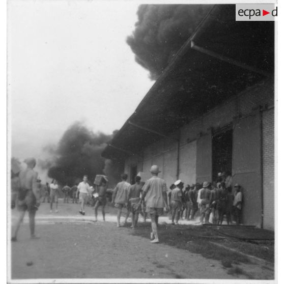A Khanh Hoi, une commune dans les environs du port de Saigon, des hommes tentent de sauver les marchandises de l'incendie déclenché par le Viet Minh, qui ravage les entrepôts. [description provisoire]