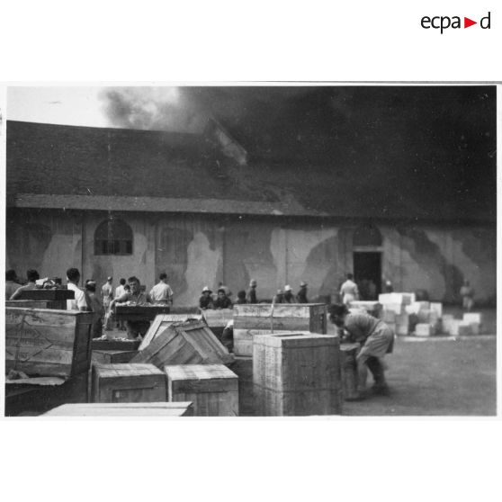 A Khanh Hoi, une commune dans les environs du port de Saigon, des hommes tentent de sauver les marchandises de l'incendie déclenché par le Viet Minh, qui ravage les entrepôts. [description provisoire]