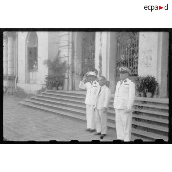 Le jour d'une conférence donnée à l'Hôtel de Ville de Saigon, le président Thinh, Mr. Torel, et un troisième représentant de l'autorité civile, se tiennent à l'entrée du bâtiment. [description provisoire]