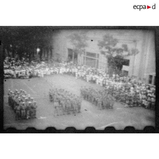 Lors d'une grande réunion, des éléments des troupes coloniales et de la Légion étrangère se tiennent au garde-à-vous, sur la place devant l'Hôtel de Ville de Saigon. [description provisoire]
