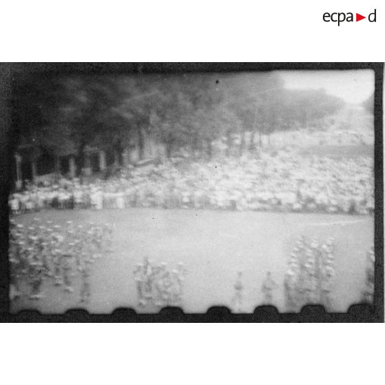 Lors d'une grande réunion, des éléments des troupes coloniales et de la Légion étrangère se tiennent au garde-à-vous, sur la place devant l'Hôtel de Ville de Saigon. [description provisoire]