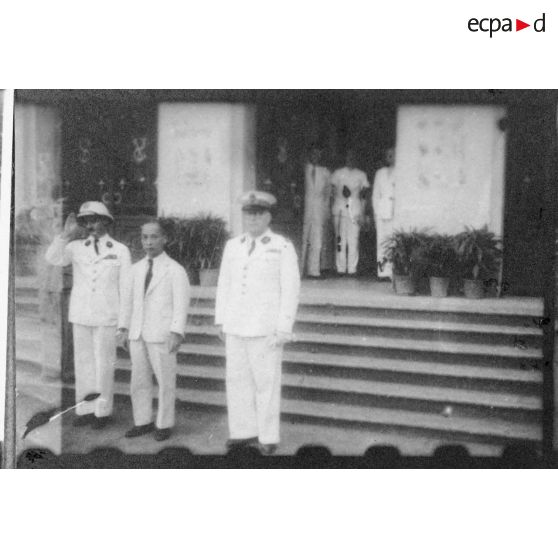 Le jour d'une conférence donnée à l'Hôtel de Ville de Saigon, le président Thinh, Mr. Torel, et un troisième représentant de l'autorité civile, se tiennent à l'entrée du bâtiment. [description provisoire]