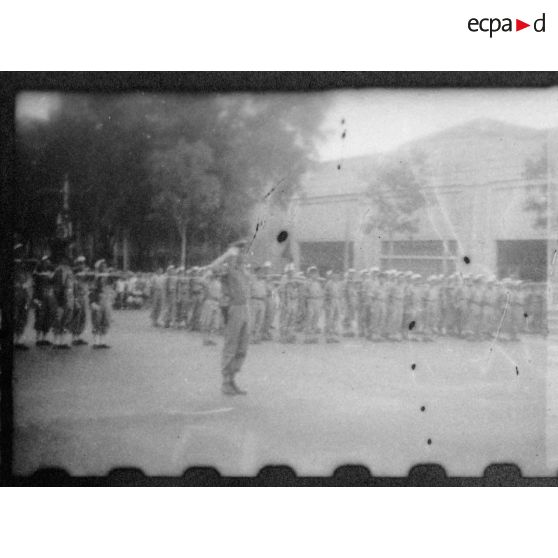 Lors d'une grande réunion, des éléments des troupes coloniales et de la Légion étrangère se tiennent au garde-à-vous, sur la place devant l'Hôtel de Ville de Saigon. [description provisoire]