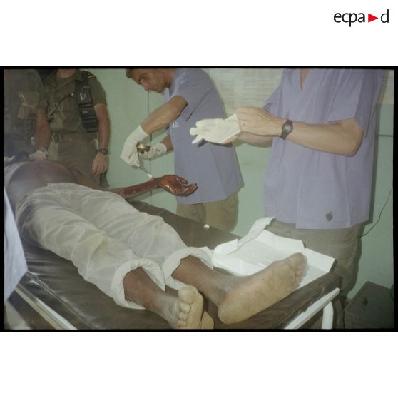 Intervention et opération chirurgicale sur un patient blessé à la main dans un dispensaire à Karama par les membres de l'antenne chirurgicale parachutiste (ACP).