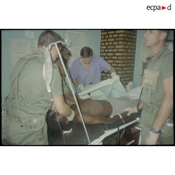 Intervention et opération chirurgicale sur un patient blessé à la main dans un dispensaire à Karama par les membres de l'antenne chirurgicale parachutiste (ACP).