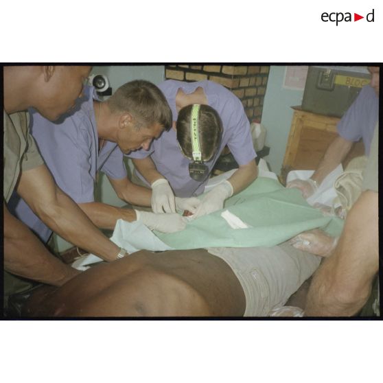 Intervention et opération chirurgicale sur un patient blessé à la main dans un dispensaire à Karama par les membres de l'antenne chirurgicale parachutiste (ACP).