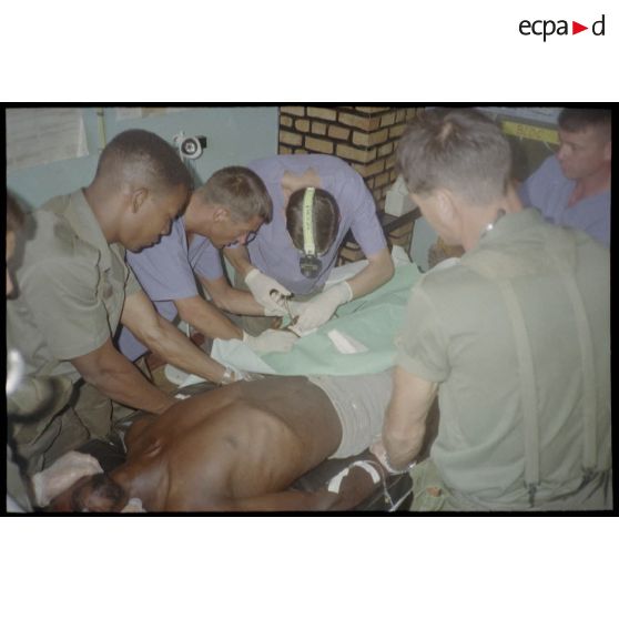 Intervention et opération chirurgicale sur un patient blessé à la main dans un dispensaire à Karama par les membres de l'antenne chirurgicale parachutiste (ACP).