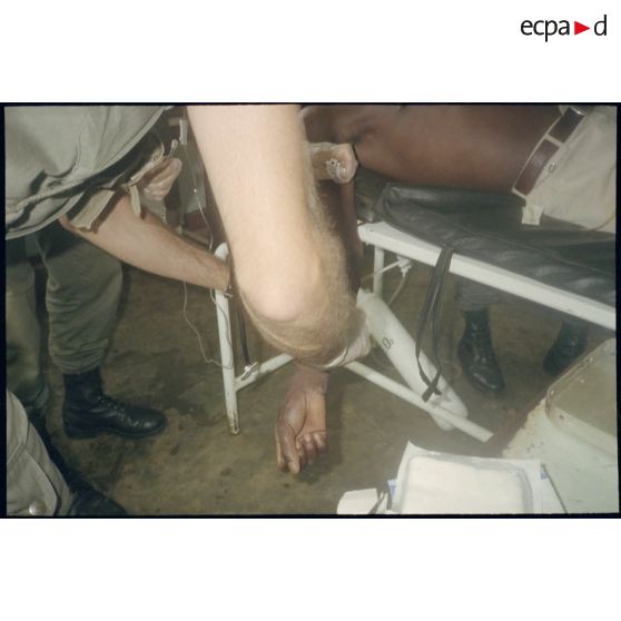 Intervention et opération chirurgicale sur un patient blessé à la main dans un dispensaire à Karama par les membres de l'antenne chirurgicale parachutiste (ACP).