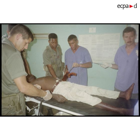 Intervention et opération chirurgicale sur un patient blessé à la main dans un dispensaire à Karama par les membres de l'antenne chirurgicale parachutiste (ACP).