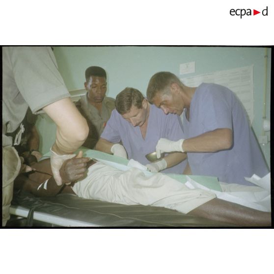 Intervention et opération chirurgicale sur un patient blessé à la main dans un dispensaire à Karama par les membres de l'antenne chirurgicale parachutiste (ACP).