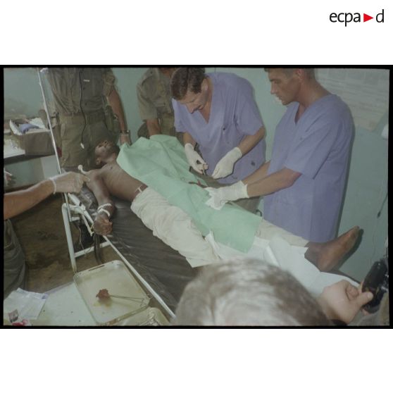 Intervention et opération chirurgicale sur un patient blessé à la main dans un dispensaire à Karama par les membres de l'antenne chirurgicale parachutiste (ACP).