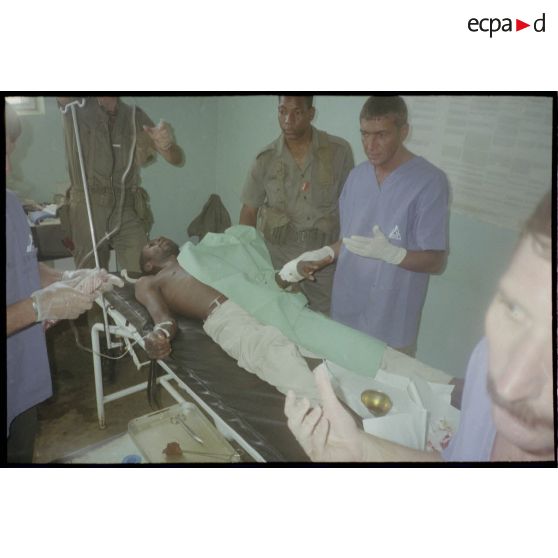 Intervention et opération chirurgicale sur un patient blessé à la main dans un dispensaire à Karama par les membres de l'antenne chirurgicale parachutiste (ACP).