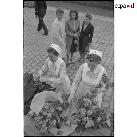 A Saint-Nazaire, des femmes, civiles et membres de la croix-rouge allemande préparent des bouquets de fleurs et guettent le retour d'un U-Boot.