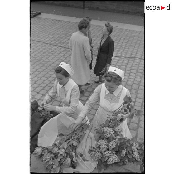 A Saint-Nazaire, des femmes, civiles et membres de la croix-rouge allemande préparent des bouquets de fleurs et guettent le retour d'un U-Boot.