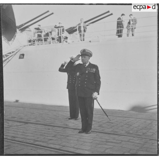 Alger. L'amiral Barthélémy salue l'étendard de la Marine Nationale.