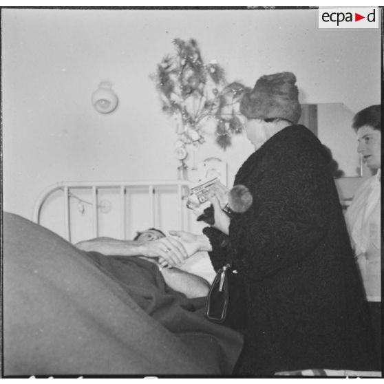 Alger. Arbre de Noël à l'hôpital Maillot. Remise de cadeaux à un grand blessé par madame  Ailleret.