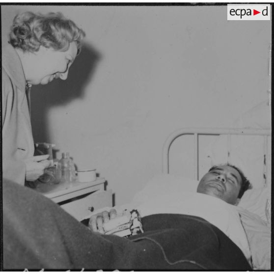 Alger. Arbre de Noël à l'hôpital Maillot. Remise de cadeaux à un grand blessé par madame de Menditte.