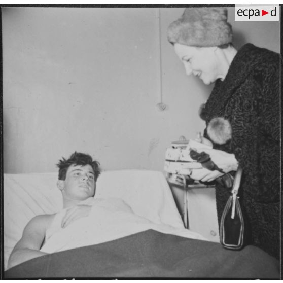 Alger. Arbre de Noël à l'hôpital Maillot. Remise de cadeaux à un grand blessé par madame Ailleret.