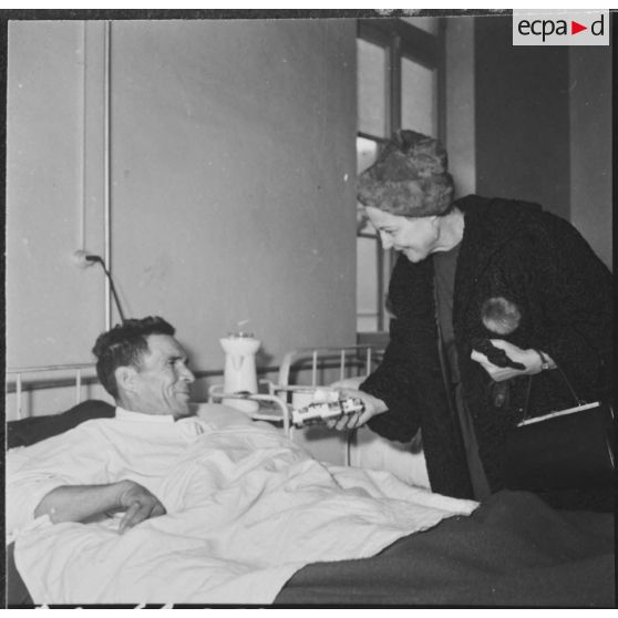 Alger. Arbre de Noël à l'hôpital Maillot. Madame Ailleret remet un cadeau à un grand blessé.