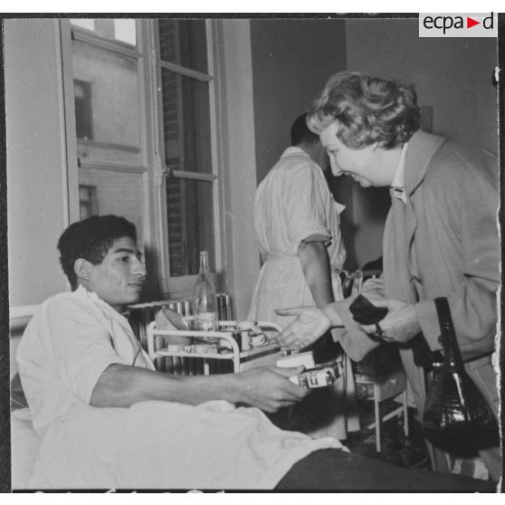 Alger. Arbre de Noël à l'hôpital Maillot. Madame de Menditte remet un cadeau à un grand blessé.