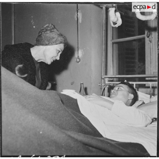 Alger. Arbre de Noël à l'hôpital Maillot. Remise de cadeau à un grand blessé par madame  Ailleret.