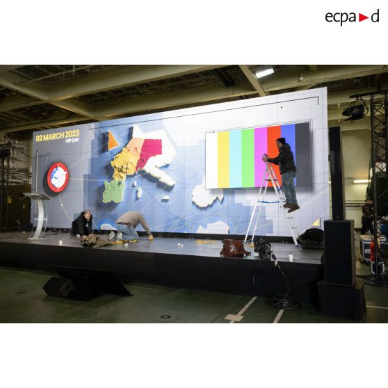 Des techniciens audiovisuels montent un écran géant à bord du porte-hélicoptèress amphibie (PHA) Tonnerre à Sète.