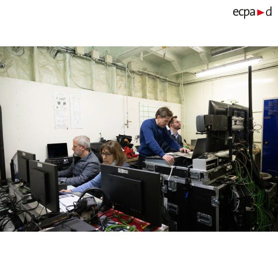 Le réalisateur-en-chef Maxence de l'ECPAD travaille avec des techniciens audiovisuels à bord du porte-hélicoptèress amphibie (PHA) Tonnerre à Sète.