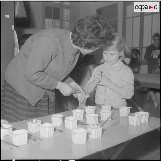 Le club du jeudi en Algérie. Une monitrice et une enfant avec des gobelets de peintures.