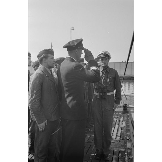 Sur le pont du sous-marin U-552 de retour de sa 5e croisière, le capitaine (kapitänleutnant) Herbert Sohler de la 7.Unterseebootsflottille passe en revue l'équipage du U-boot en compagnie de son commandant, Erich Topp.